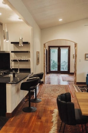 Cocina moderna con barra, una mesa de comedor con sillas y vistas al exterior a través de un ventanal.