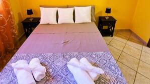 Ein Hotelzimmer mit einem Bett, zwei Nachttischen, einer Wand mit drei Bildern und einer gemusterten Bettdecke.