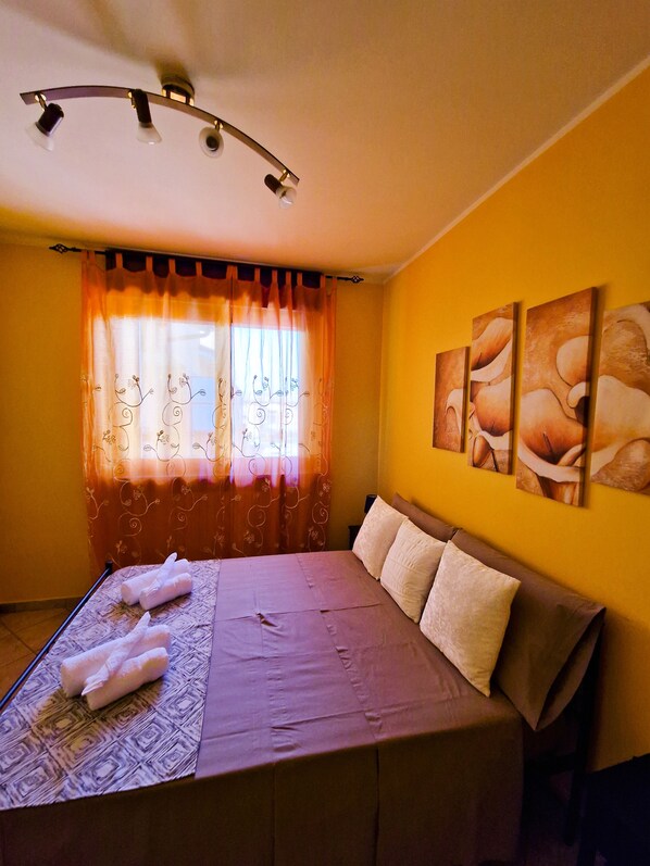 Una camera da letto con un letto, tende e opere d'arte alle pareti.