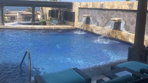 A pool area with a stone wall, a water feature, and lounge chairs. - Vacations smutny 
 (Cabo San Lucas)