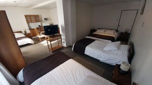 A hotel room with two beds, a desk with a television, a microwave, and a small kitchen area. - Hotel Esmeralda (Castro)