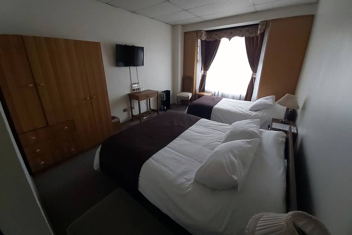 Una habitación de hotel con dos camas, televisión, escritorio y armario.