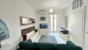Un salon moderne avec un canapé vert, un téléviseur à écran plat et un coin repas comprenant une table et des chaises.