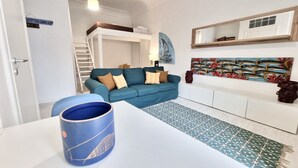 Un salon moderne avec un canapé bleu, une table basse blanche et un tapis à motifs.
