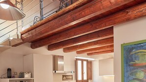 A compact kitchen with wooden beams, a dining area with a table and chairs, and a sofa. - Cala Rossa in Siracusa (Syracuse)