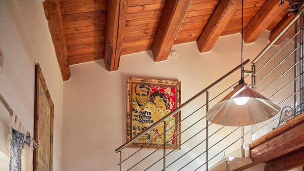 A staircase with a metal railing leading to a second floor, a dining area with a white table and blue chairs, and a kitchen with an oven and a refrigerator. - Cala Rossa in Siracusa (Syracuse)