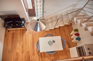 A modern kitchen with wooden flooring, a dining area with a table and chairs, and a staircase with a metal railing. - Cala Rossa in Siracusa (Syracuse)