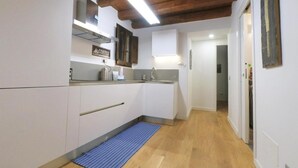 A compact kitchen with white cabinets, a coffee station, and a wooden ceiling. - Cala Rossa in Siracusa (Syracuse)