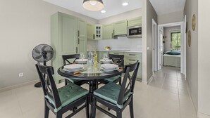 Une cuisine moderne avec des meubles de couleur verte, une table à manger avec des chaises et un ventilateur de plafond.