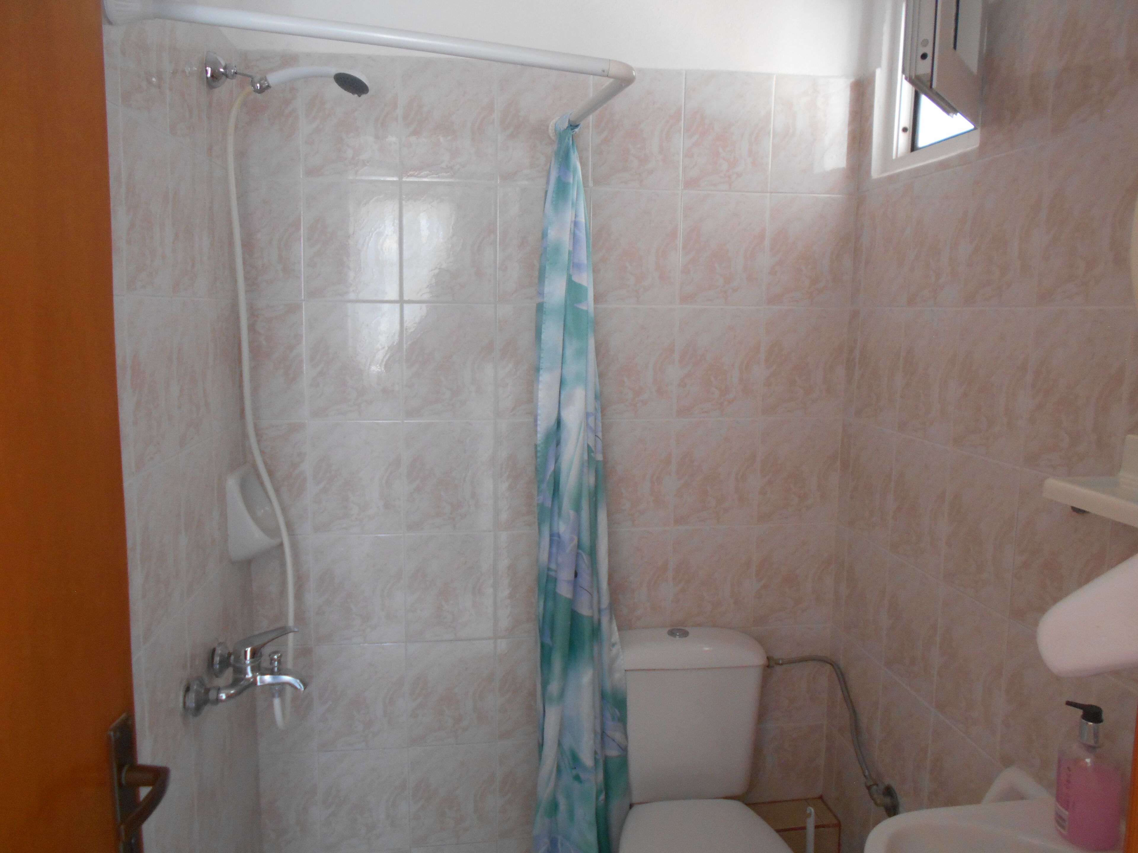 Een badkamer met douche, toilet en wastafel.