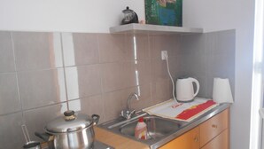 A kitchen with a stove, kettle, and sink. - Garifalia Studio's (Faistos)