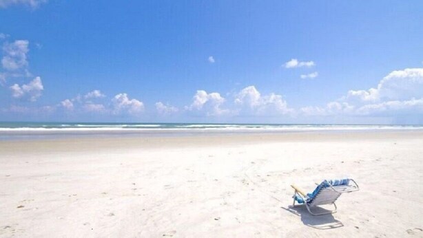A beach with a single blue and white beach chair on the sand. - Ocean Village Club-Sleeps 4 with First  Floor Access and Screen Porch (St. Augustine)