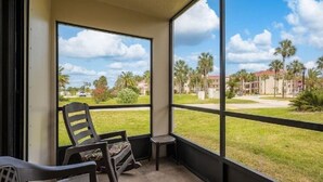 A balcony with a view of a residential area, featuring palm trees and houses. - Ocean Village Club-Sleeps 4 with First  Floor Access and Screen Porch (St. Augustine)