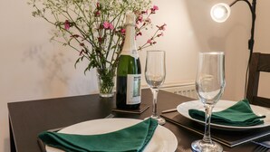 Et spisebord dækket med en vinflaske, to vinglas og en blomstervase.