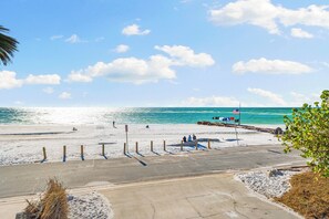A beach with a concrete walkway, a lifeguard tower, and a clear view of the ocean.