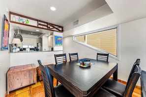 A dining area with a wooden table, chairs, and a window with blinds. - Fanta-Sea 47 by Beachside Management (Siesta Key)