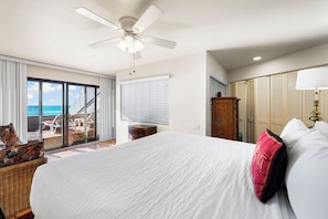 A hotel room with a large bed, a ceiling fan, a view of the ocean through a sliding door, and a wooden wardrobe. - Fanta-Sea 47 by Beachside Management (Siesta Key)