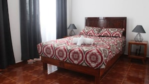 A neatly made bed with a patterned bedspread, two bedside lamps, and a wooden nightstand with a lamp.