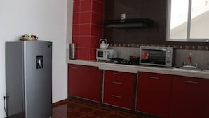 A kitchen with red cabinets, a stainless steel refrigerator, a microwave, and a toaster oven.