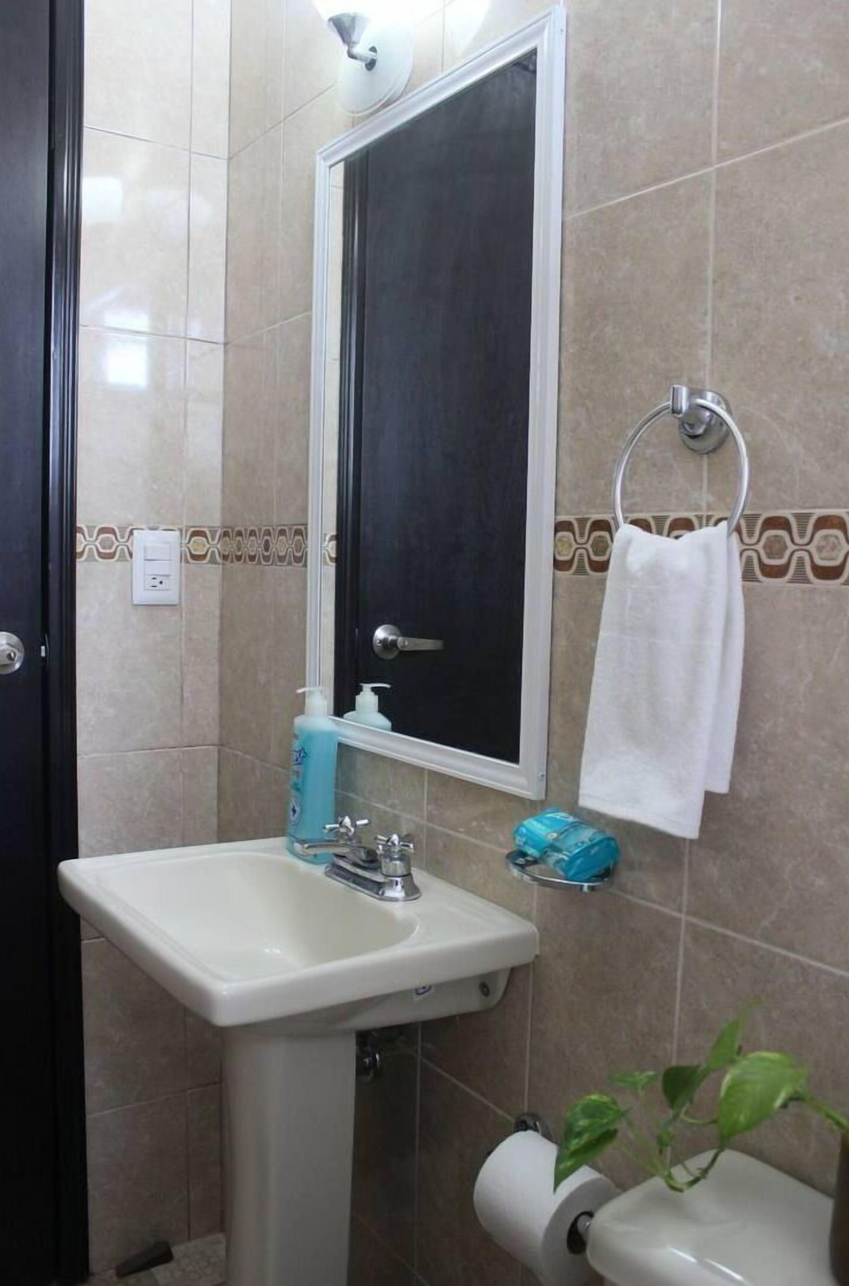 Een badkamer met een witte wastafel, een spiegel, een handdoekhouder en een toilet.