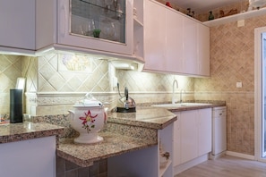 A kitchen with white cabinets, a granite countertop, a teapot, and a coffee maker. - San Pedro del Mar (San Pedro de Alcántara)