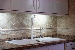 A kitchen with a white countertop, a sink, and a faucet.