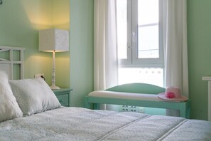 A bedroom with a bed, a nightstand, a lamp, a window with curtains, and a hat on the window sill. - San Pedro del Mar (San Pedro de Alcántara)