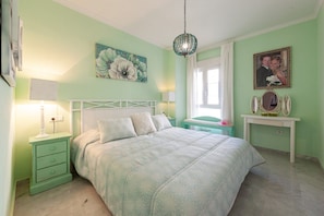 A bedroom with a bed, nightstands, a dresser, a mirror, and wall art.