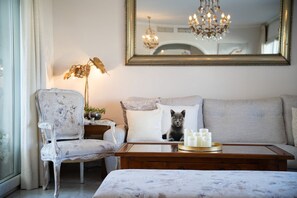A room with a sofa, a chair, a table with candles, and a mirror on the wall.