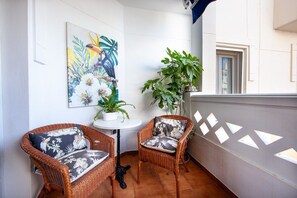 A balcony with wicker chairs, a small table, and a potted plant.