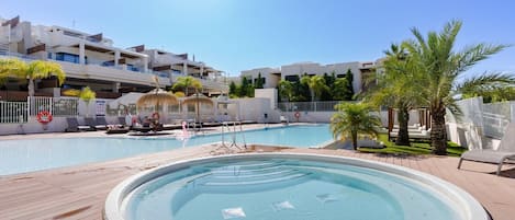 Et poolområde med et spa, liggestole og en palme.