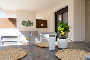 A modern outdoor seating area with a wooden table, woven placemats, and a potted plant.