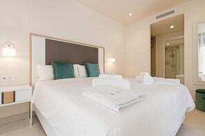A hotel room with a bed, bedside tables, a mirror, and a shower area.
