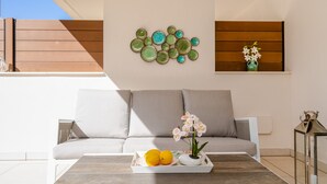 Ein modernes Wohnzimmer mit einer Couch, einem Couchtisch mit Früchten und einer Vase, sowie dekorativen Tellern an der Wand.