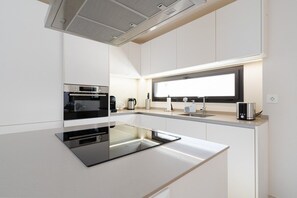 A modern kitchen with a central island, built-in oven, and a window above the sink.