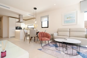 A modern living room with a sofa, a coffee table, and a dining area with chairs.