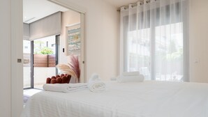 Ein Hotelzimmer mit einem großen Bett, einer Tür zu einem Balkon und Blick auf Grünflächen.