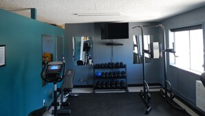 A gym with exercise equipment, a treadmill, a TV, and a window with natural light. - The Shepherd's Inn (Charlie Lake)