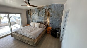 Ein modernes Schlafzimmer mit einem großen Bett, einem Deckenventilator und einer Wand mit Used-Look.