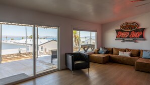 A spacious living room with a large sliding glass door leading to a balcony, a black leather armchair, and a brown sectional sofa. - Jet Boat Billy's Speed Shop Havasu (needles)