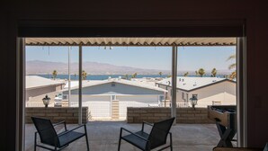 A room with a large window overlooking a residential area with houses and mountains. There are two chairs in the foreground. - Jet Boat Billy's Speed Shop Havasu (needles)