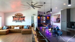 A modern kitchen with a bar area, a ceiling fan, and a neon sign. - Jet Boat Billy's Speed Shop Havasu (needles)