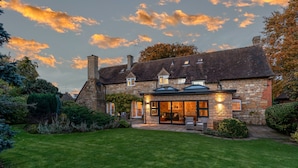 Une maison en pierre avec une pelouse bien entretenue et un espace patio.