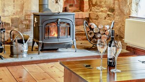 Une pièce chaleureuse avec un poêle à bois, une bouilloire en métal et une table avec des verres à vin.
