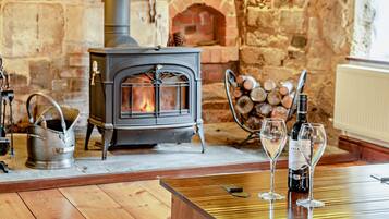 Une pièce chaleureuse avec un poêle à bois, une bouilloire en métal et une table avec des verres à vin.