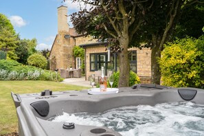 Una vasca idromassaggio con acqua, una bottiglia di vino e un tavolo con sedie in un giardino.