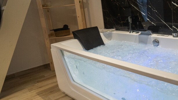 Une salle de bain moderne avec une grande baignoire, un plancher en bois et un pare-baignoire en marbre.