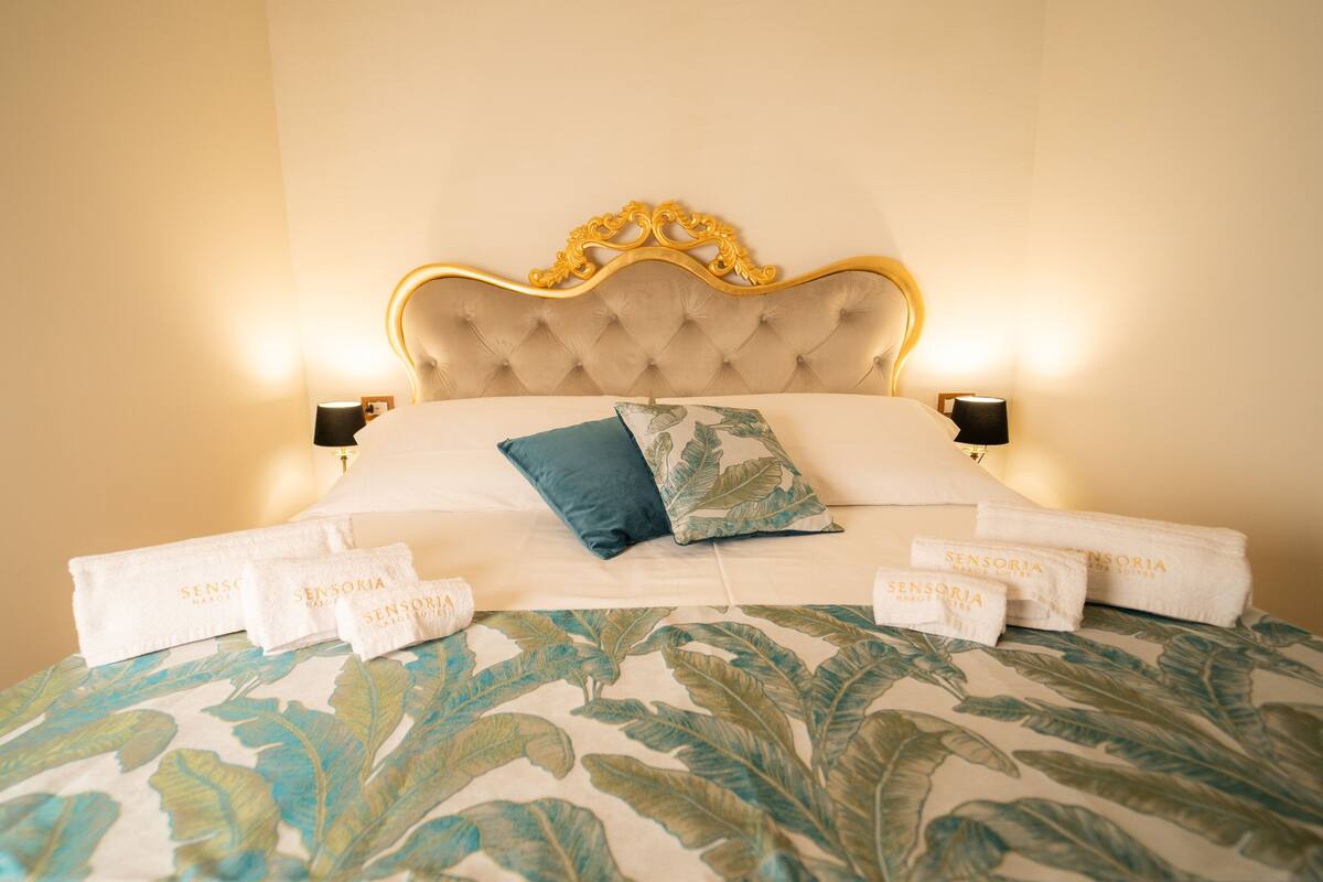 A bed with a tufted headboard, two pillows, and a floral-patterned bedspread.