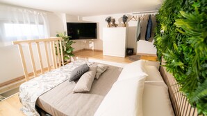Une chambre à coucher avec un lit, une télévision, une plante et un portant à vêtements.