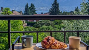 A balcony with a view of mountains and a lake, a plate with pastries, and two cups. - Ecrin Vue Lac (Sévrier)